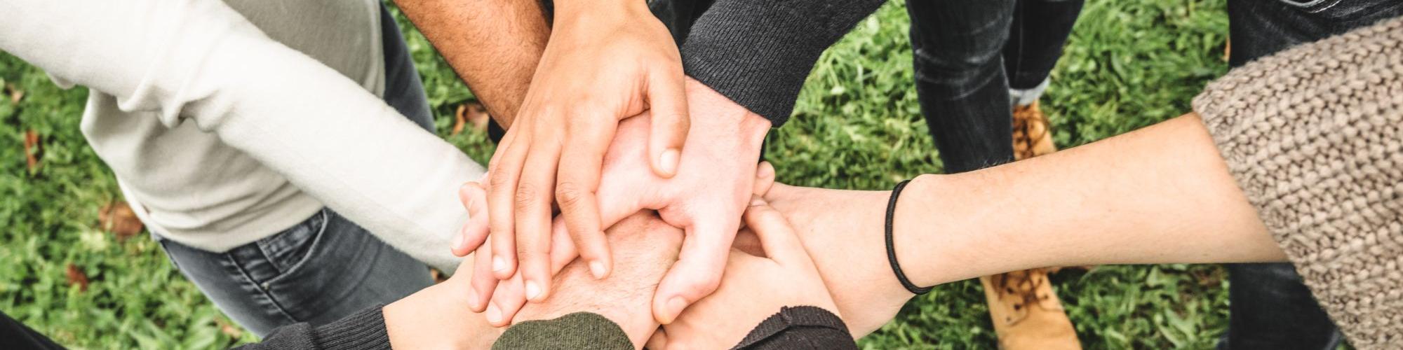 group of people putting their hands in a group huddle